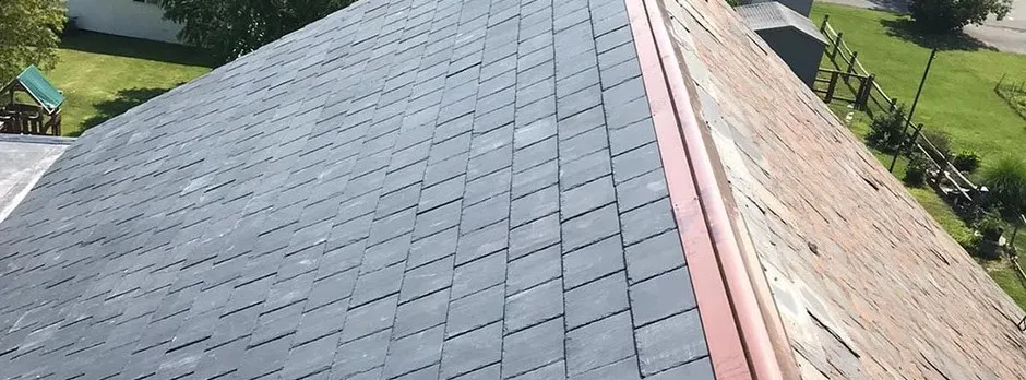 Close-up of a slate roof with a copper valley, showing the material range SGM Home Restoration installs.