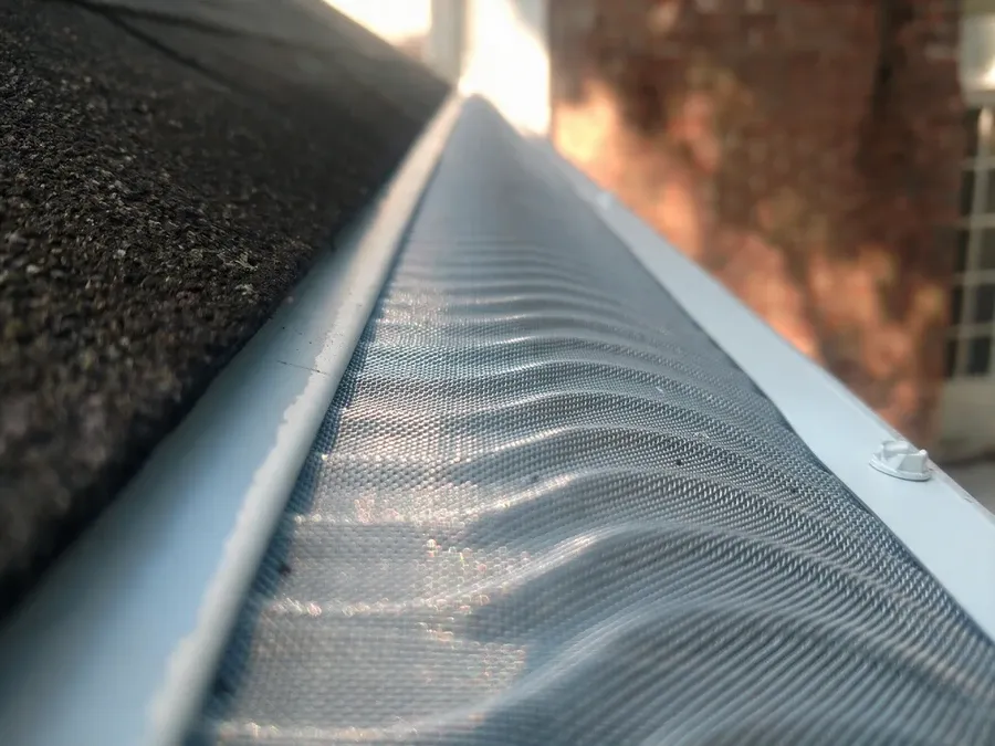 Close-up of a wavy micro-mesh gutter guard installed on an aluminum gutter.