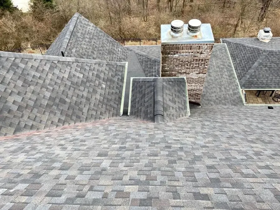 Finished gray architectural asphalt shingle roof with multiple hips, valleys, and a brick chimney.