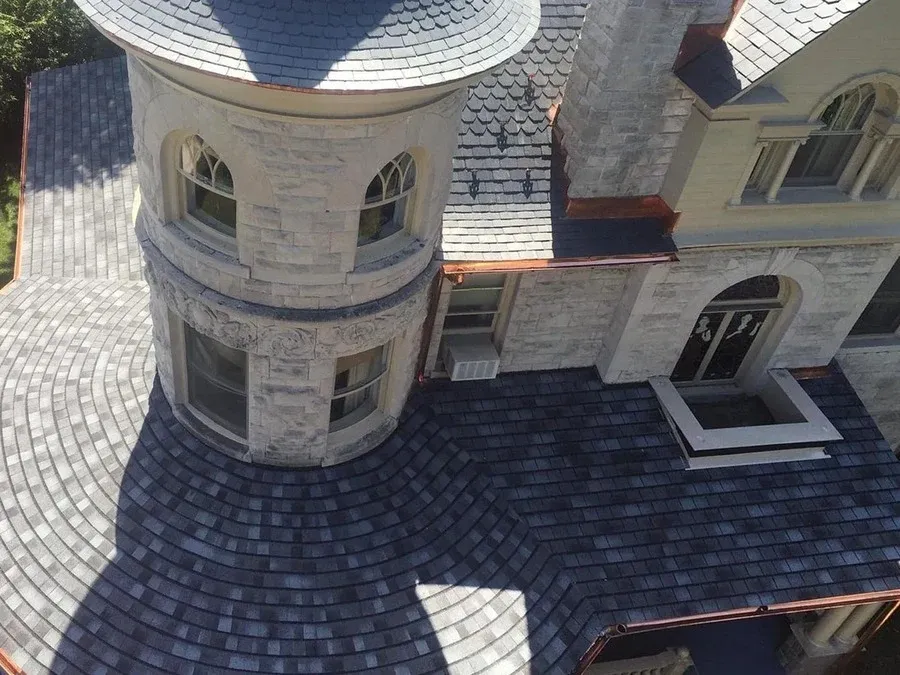 Ornate turret roofline with slate tiles and copper trim on a Victorian-style home.