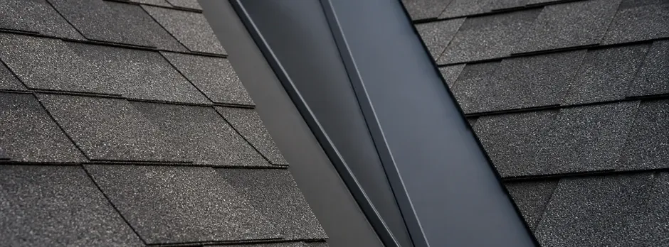 Close-up of metal valley flashing meeting architectural asphalt shingles.
