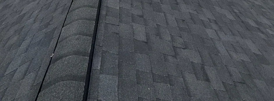 Close-up texture of dark architectural asphalt shingle courses.