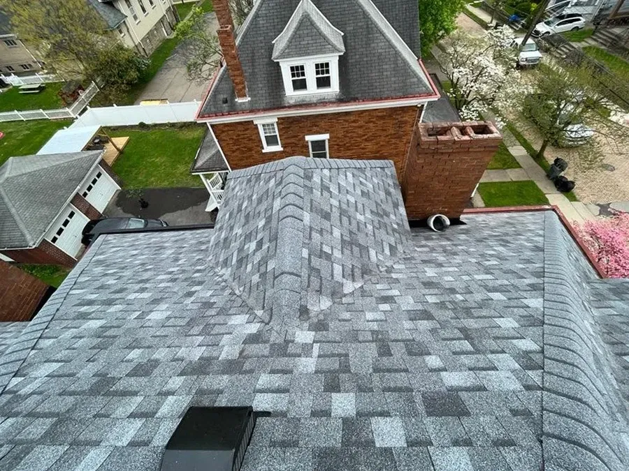 Finished gray architectural asphalt shingle roof with a dormer window and brick chimney on a Somerset County home.
