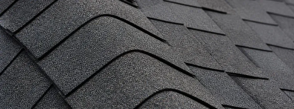 Close-up of charcoal ridge cap shingles along a roof ridge.