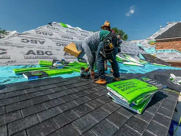 Roofing crew installing underlayment and materials on a residential roof.