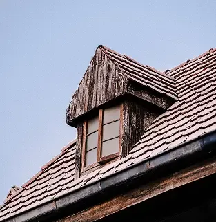 Weathered dormer window before roof restoration.