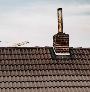 Finished brown tiled roof with chimney after completion.