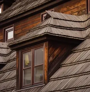 Rich dark brown shingles on a steep roof section after replacement.
